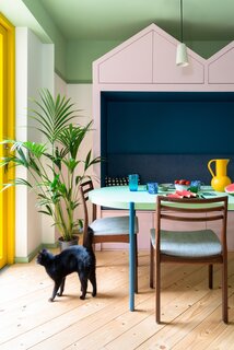 A palm sits in the corner of the dining space, near a glazed door that connects the interior to the garden. “In summertime, they can open the door and it almost feels like the dining table is outside,” says architect Catrina Stewart. 