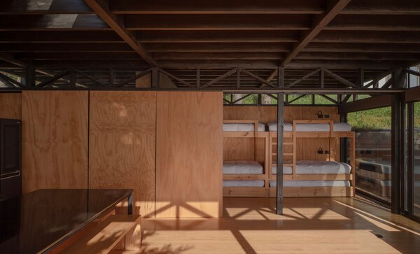 A series of plywood panels separate the large common area of the cabin from the smaller private areas. They slide open to reveal the sleeping area, outfitted with custom bunk beds. 