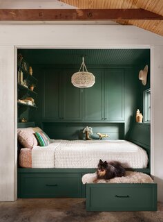 A splash of dark green paint in the sleeping nook introduces an old world drama to the space. The paint color is Billiard Green from Sherwin Williams. The crochet pendant is from World Market, and the brass bull was an eBay find. The couple's dog Waylon lounges in the pull-out dog bed drawer.