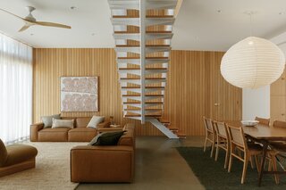 A steel staircase connects the living room to the new second story while acting as a functional sculpture in the space. Cameron repurposed the timber paneling from another building site.