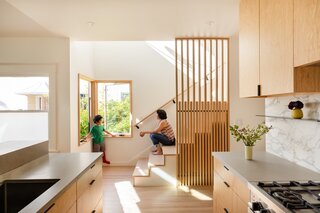 Lee Buchanan of Lee Build created a screen of white ash slats beside the kitchen as well as the entry. "The stairs are beautifully integrated into the kitchen so the kids and I are always talking and someone is always sitting on the bottom steps,