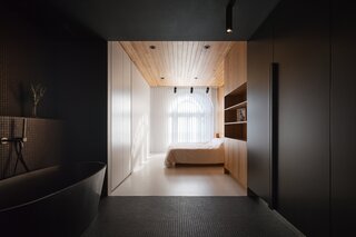The ceiling and built-in storage wall in the bedroom are fabricated from American white oak, while the opposite wall and floor has the same grayish-white tone found in the rest of the apartment.