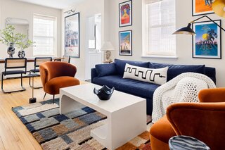 The denim-colored sofa is from West Elm (a nod to the jean shorts featured in Tyler's "Sunday in the Park" poster), while the pumpkin-hued armchairs were a splurge at Soho Home. 