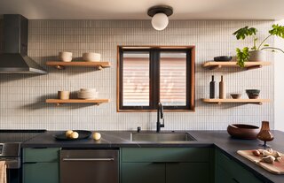 The new kitchen features ceiling-to-countertop tiles in a grid pattern, which reappears throughout the home. The globe flush mount overhead is from Anthropologie, while the hardware is from Altas Homewares and Alno Hardware.