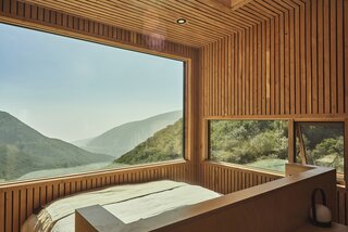 The sleeping area, outfitted with a California king-size bed with a built-in headboard made from Baltic birch, showcases expansive views of the mountain landscape, connecting guests to nature.