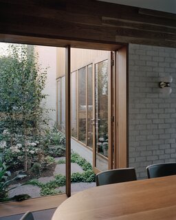 There are eight outdoor spaces, or yards, of different sizes, which gives rise to the name of the house. This small courtyard is located off the dining room, and helps to connect the interior to the outdoors. "The selection of reclaimed brick has given this house a coherence that meshes perfectly with the focus on nature of the eight outdoor yards, and the cream paint contrasts wonderfully with the green planting throughout,