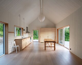Three large windows allow the surrounding nature to enter the house from different angles during the day.  “We like the way the house opens up with large windows facing the mountain at the back, which makes nature very present even when you are inside,” says Helena. <span style="font-family: Theinhardt, -apple-system, BlinkMacSystemFont, &quot;Segoe UI&quot;, Roboto, Oxygen-Sans, Ubuntu, Cantarell, &quot;Helvetica Neue&quot;, sans-serif;">The custom dining table—which was made by a local artisan—is located in front of west-facing windows that frame the sunset in the evenings. The table can be easily moved inside or out depending on the weather.</span><span style="font-family: Theinhardt, -apple-system, BlinkMacSystemFont, &quot;Segoe UI&quot;, Roboto, Oxygen-Sans, Ubuntu, Cantarell, &quot;Helvetica Neue&quot;, sans-serif;"> </span>