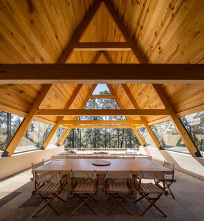 Under the extension of the A-frame is the dining area and a large sofa for gathering. According to Pablo, the family gathers there in all weather. "Listening to the rain on the roof and in the trees is a wonderful experience," he notes.