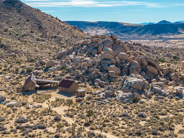 A Joshua Tree-lined driveway leads to the remote home, nestled among historic boulders.