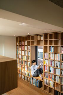 A wall on the second level features a built-in bookcase with a reading nook.