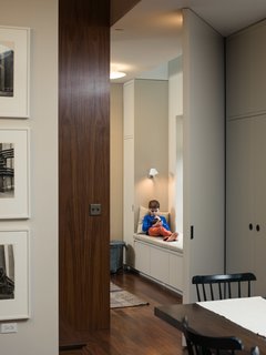 Houldin, 10, curls up in the playroom nook which is directly under a side skylight that Pulltab added in order to make the interior rooms inhabitable, as per New York City building code. The custom millwork around the window seat is painted in Rainy Day by Fine Paints of Europe.