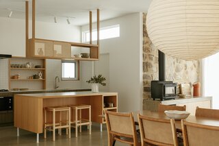 The open-plan kitchen, dining and living room honors the home's original design and heroes the existing stone wall.